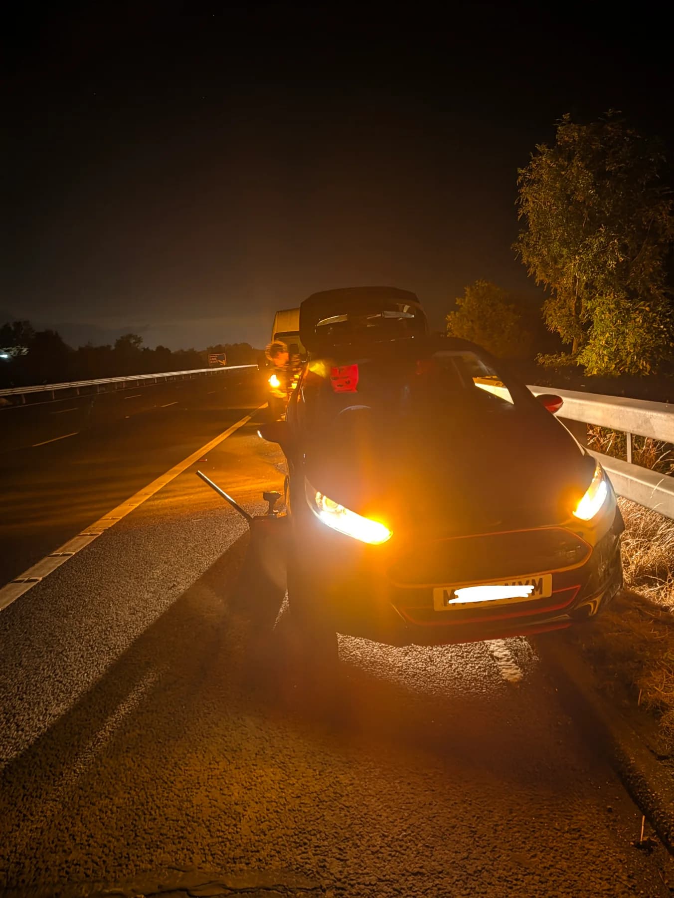 Roadside tyre call-out with hazard lights illuminating the car